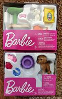 Two boxed Barbie accessory play sets each containing pet toy figures and accessories with Barbie branding.