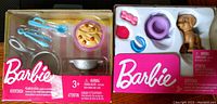 Shows two Barbie accessory play sets side by side inside their original packaging, both new in box.