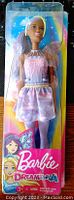 Front view of Barbie Dreamtopia doll in packaging showcasing purple hair, pink top, purple skirt, and fairy wings.