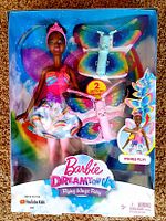 Front view of Barbie Dreamtopia Flying Wings Fairy doll in original packaging, showing doll wearing pink crown, colorful dress, and 2 sets of multicolored butterfly wings included in the box.