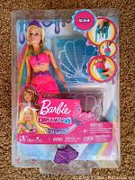 Front view of unopened Barbie Dreamtopia mermaid doll in packaging, showing doll dressed in pink mermaid outfit and slime molds included.