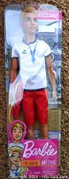 Ken doll in original packaging, dressed as a lifeguard with white shirt, red shorts, and whistle accessory.