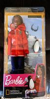 Front of unopened Barbie National Geographic Polar Marine Biologist doll in box. Doll wearing red coat with hood, dark pants and boots. Penguin graphic and brand logos visible.
