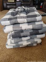 Stack of six buffalo plaid chair cushions showing the color pattern and tufting