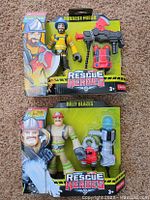 Photo shows two Rescue Heroes action figures packaged. One labeled Forrest Fuego with firefighter axe and walkie-talkie. Other labeled Billy Blazes with water cannon and fire hose. Both new in original flea market style blister packaging with artwork.