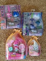 Four Trolls World Tour figures in original packaging with accessories, new in box.