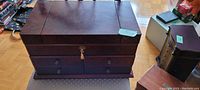 Closed view of the Bombay Co. jewelry box with cherry wood finish and lock on the front.