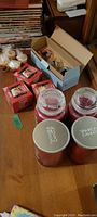Four large Yankee Candle jars visible, three with silver metal lids, one with glass lid, along with three red boxes of Yankee Candle tealights.