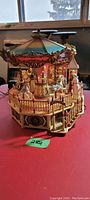 Full view of carousel on table showing horses, canopy, fence, and overall design