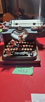 Front view of the electric music box shaped like a vintage typewriter with multiple mouse figurines on keys and typebars and paper inserted.