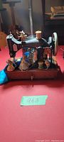 Front view of the sewing machine music box showing multiple mice figurines in colorful clothing positioned around the machine on a wooden base.
