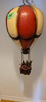 Front view of the hand painted hot air balloon with cream and orange-red vertical panels and basket below