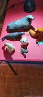 Overall lot of wood and soapstone hand carvings on red table, showing multiple seal and marine animal sculptures of varying sizes and materials.