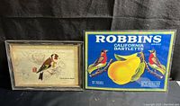 Two bird-themed laminated prints side by side on dark background; one is vintage crate label for Robbins California Bartlett pears featuring birds and pear, the other a framed finch print