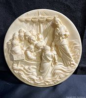 Full view of the round alabaster plate depicting Cristo Cammina Sulle Acque showing Jesus walking on water with followers in relief sculpture.