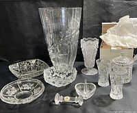 Full collection showing multiple clear crystal and cut glass pieces including vases, silverware rests, sugar bowl, and dishes