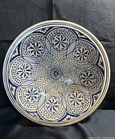 Full view of circular blue and white Moroccan style clay plate with geometric and floral motifs.