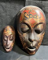 Two Indonesian wooden masks placed upright showing full front detail.