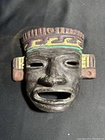Front view of the vintage Aztec black clay mask with colorful hand-painted details on forehead and ears.