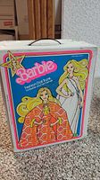 Front view of vintage white Barbie fashion doll trunk with colorful label showing Barbie dolls in 1970s fashion, branding, and measurements.