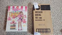 Two boxed Barbie dolls side by side on carpet