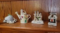 Clear view of five vintage china cat miniature figurines placed on a wooden shelf, showing variety in design and detailing
