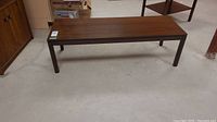 Full view of rectangular wood coffee table with dark brown finish and four straight legs, showing overall condition and size.