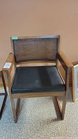 Frontal view of chair showing wood frame, black leather padded seat, and lattice backrest