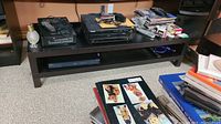 Front view of the wood media stand showing contents on top and bottom shelf and chipping on front left leg.
