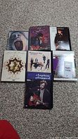 Photo with 8 music DVDs displayed on carpet floor showing titles by Santana, Janet Jackson, Eric Clapton, Fleetwood Mac, Sarah McLachlan, Pink Floyd, and Crossroads Guitar Festival.