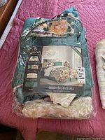 Photo of the packaged bedding set showing the product details including the 8-piece queen bed ensemble with reversible comforter, shams, sheet set and bedskirt.