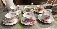 Set of 6 Royal Albert teacups with matching saucers displaying varied floral designs on a kitchen counter.