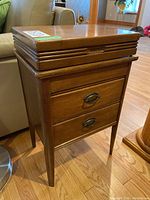 Sewing table closed showing wood finish and two drawers with brass handles.