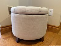 Side view showing round shape, fabric upholstery, and angled wood legs