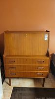 Full front view of teak secretary desk against wall