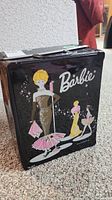 Front view of vintage Barbie metal case with 1960s style illustrated Barbie figures in dresses.