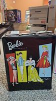 Front view of the black Barbie fashion trunk with color illustrations of Barbie dolls and the Barbie logo.