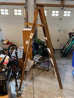 Side view of the wooden painter's ladder showing A-frame structure, flat steps, and paint shelf at top.