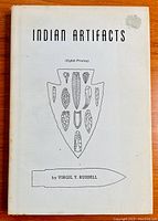 Front cover of the 1962 book 'Indian Artifacts' showing the title, author, and black line drawings of various arrowheads and a spear point.