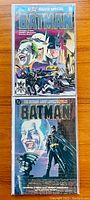 Photo showing two Batman movie special comics, one stacked on top of the other, with colorful Batman and Joker related artwork.