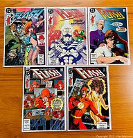 Top view of five Flash comics in protective sleeves laid out on a wooden surface, showing full covers of issues #35 to #39.