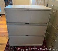 Front view of a single steel filing cabinet showing three drawers and lock at top