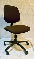 Single brown office chair with fabric upholstery, curved backrest, cushioned seat, and five caster wheels.