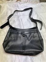 Front view of the black leather Longchamp shoulder bag showing the adjustable strap and front design detail