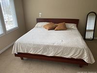 Full view of king size bed frame with bedding on it, showing the wooden frame and headboard design.