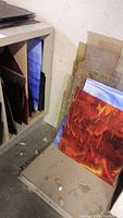 Shelf storage showing red/orange swirl panel leaning against a cubby with various other colored panels