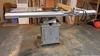 Full view of table saw mounted on wooden stand with sliding aluminum extension table