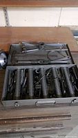Full view of the open metal case showing various taps, dies, T-handle wrenches, and measuring tools arranged inside.