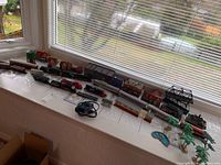 Overall view of locomotives, cars, buildings, diorama accessories and transformer on windowsill