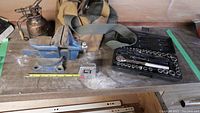 Photo showing all items on the workbench: bench vise, socket set in case, vintage oil can, tool bag, and tape measure (not included).